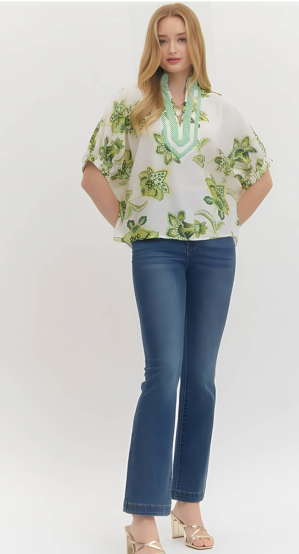 Woman wearing a floral blouse and blue jeans on a white background