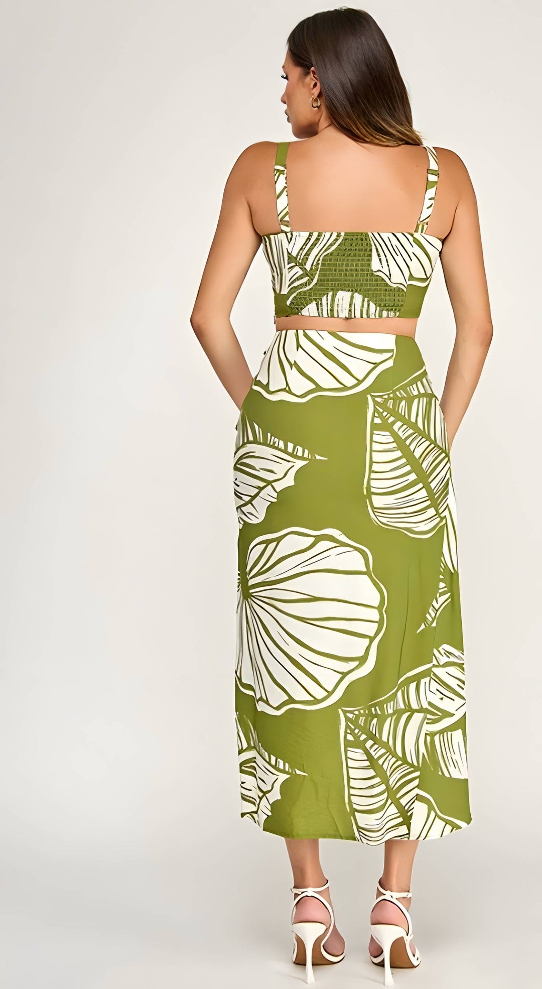 Woman wearing a green dress with white floral patterns on a plain background