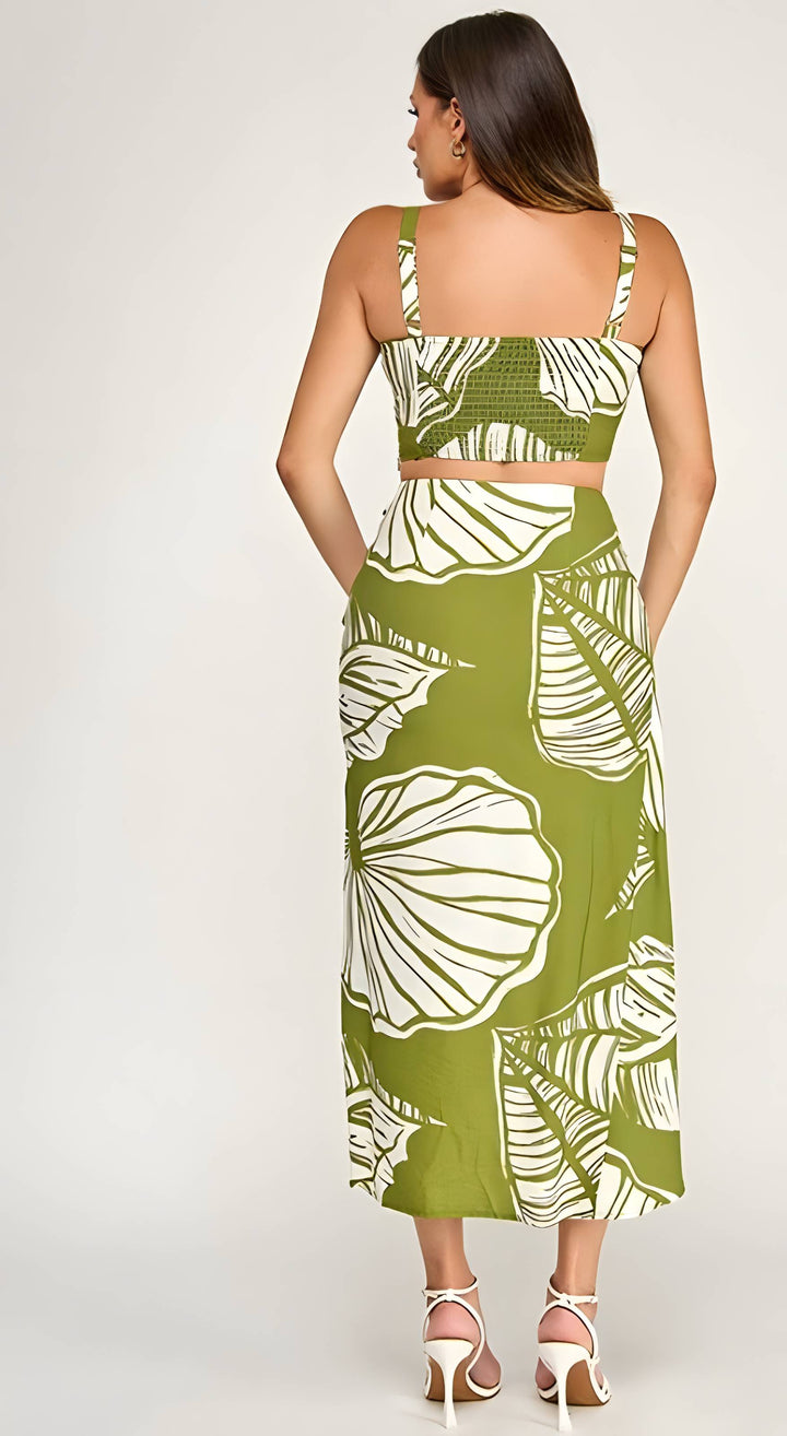 Woman wearing a green dress with white floral patterns on a plain background