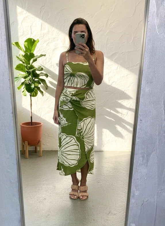 Person wearing a green and white dress with leaf patterns in front of a mirror.