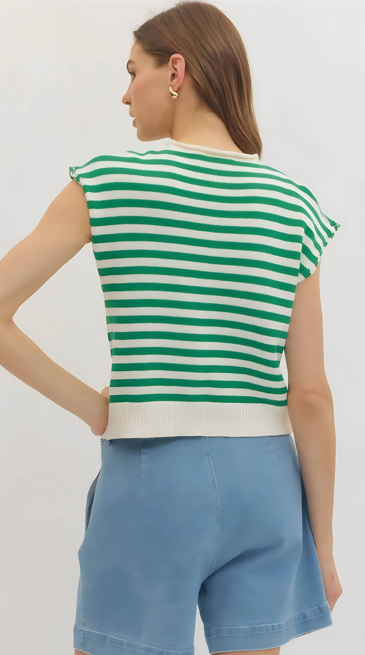 Person wearing a green and white striped sleeveless top with blue shorts on a plain background