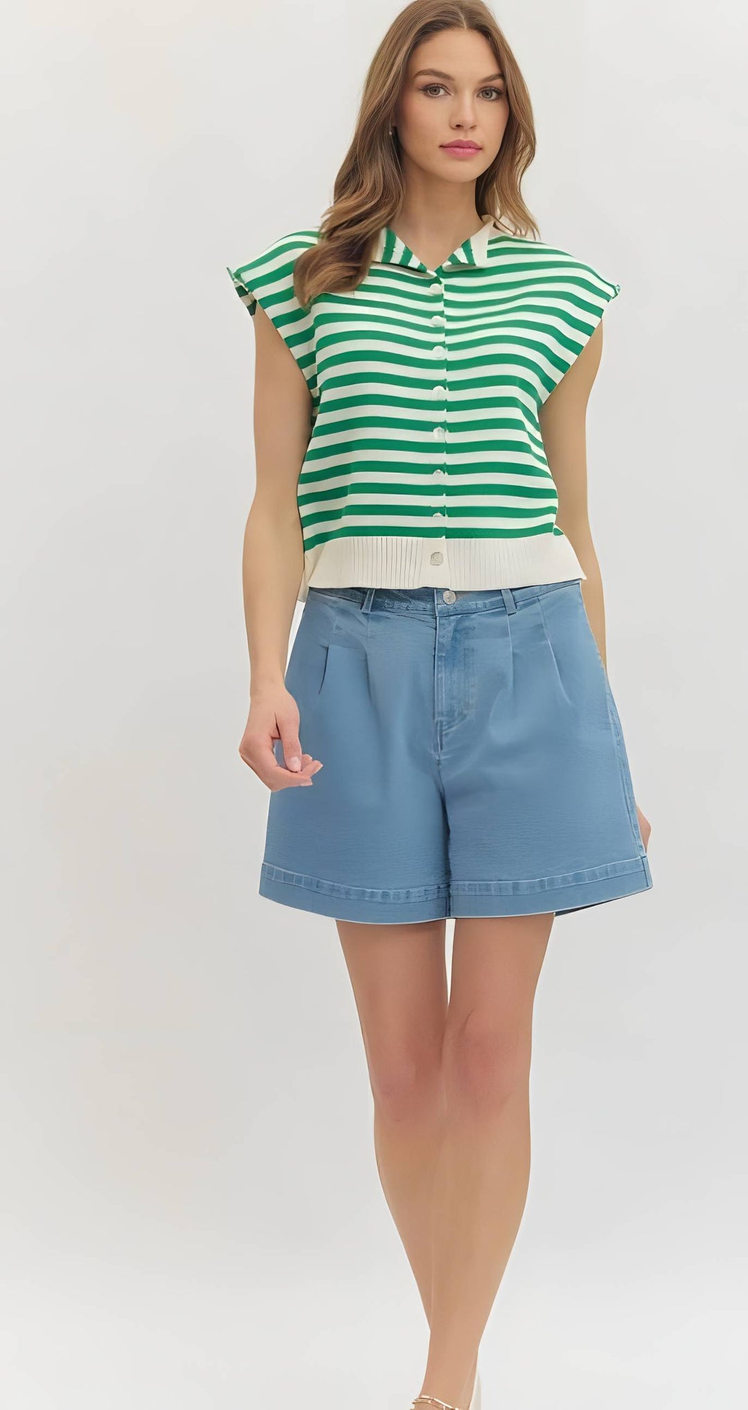 Woman wearing a green and white striped shirt with blue shorts on a white background