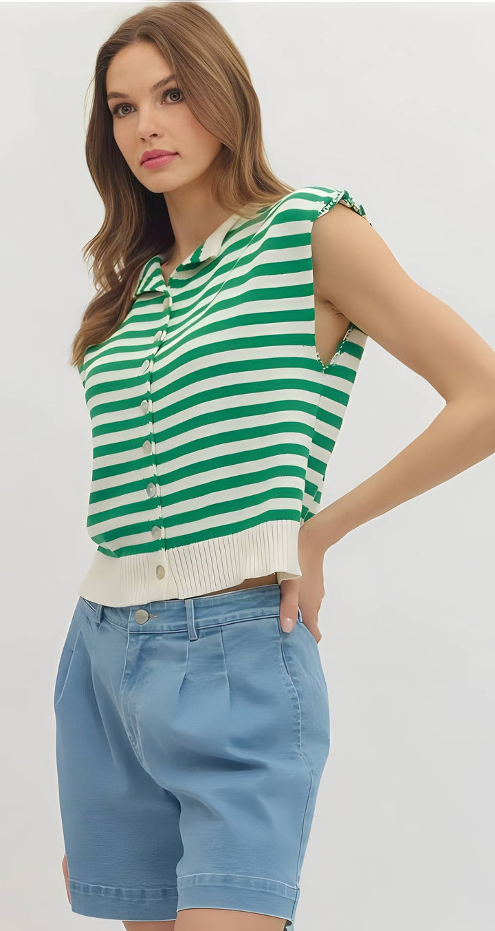 Woman wearing a green and white striped sleeveless top with blue shorts on a plain background