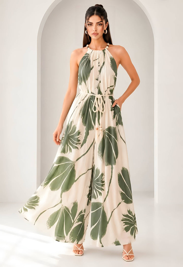 Woman wearing a long, leaf-patterned jumpsuit against a neutral background