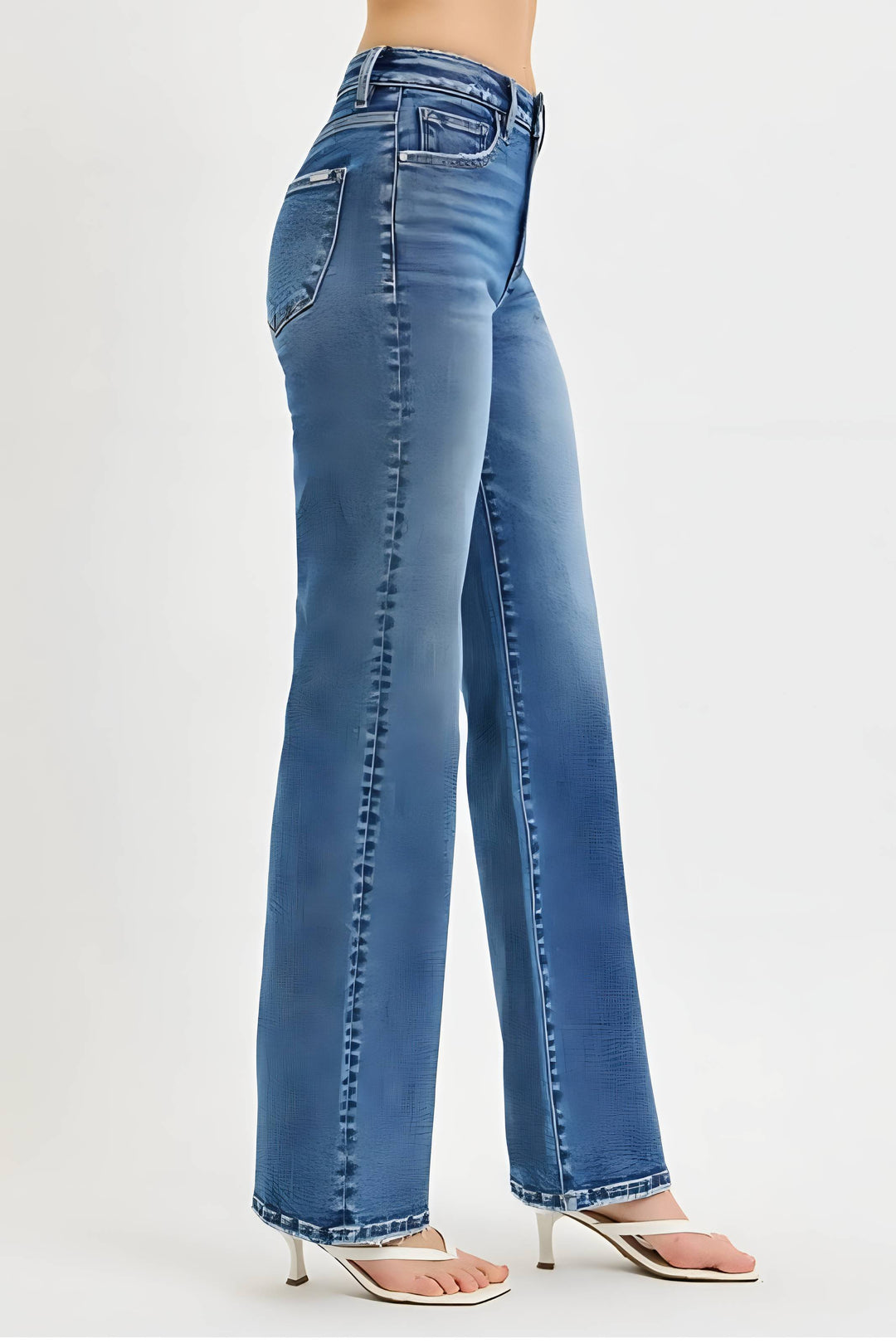 A person wearing blue wide-leg denim jeans with a faded wash and silver-toned metal rivets down the front of the legs, paired with clear high-heeled sandals against a light gray studio background.