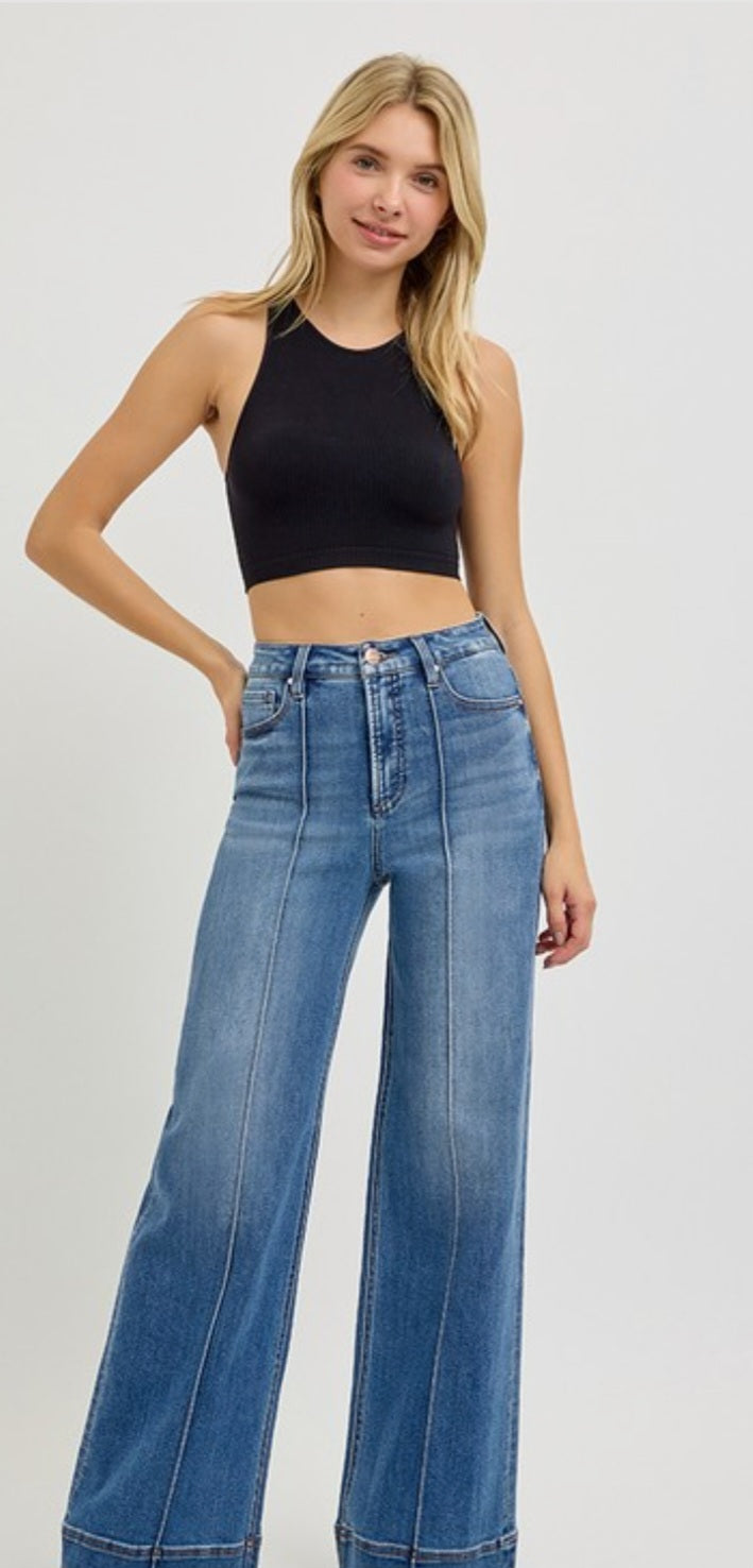 Woman wearing a black crop top and blue jeans on a white background