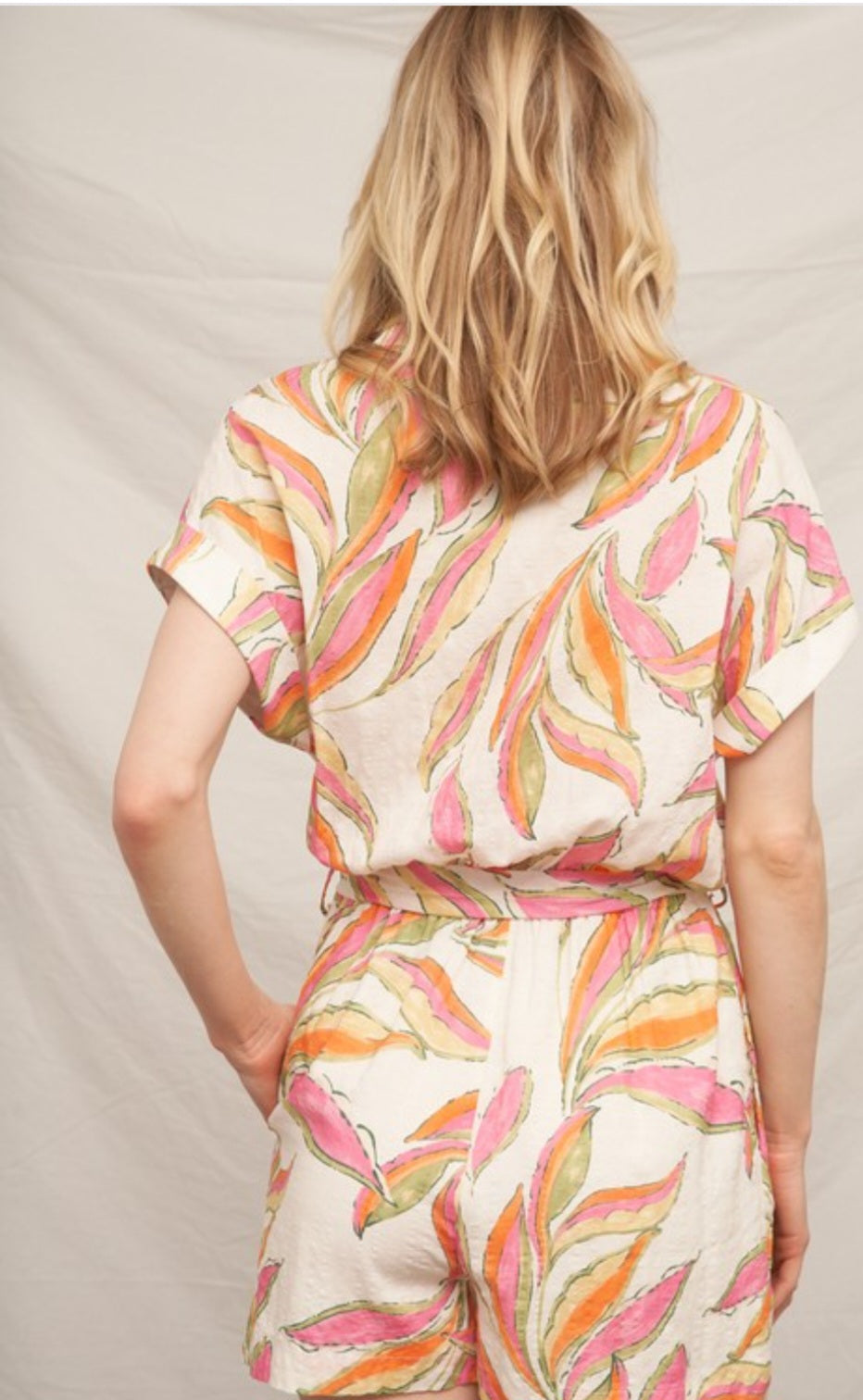 Woman wearing a colorful patterned romper against a plain background