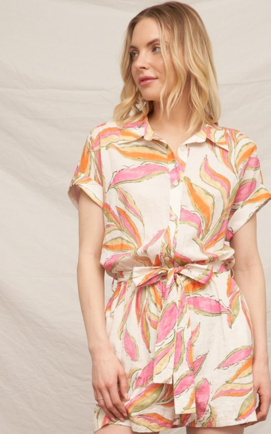 Woman wearing a colorful patterned romper against a neutral background