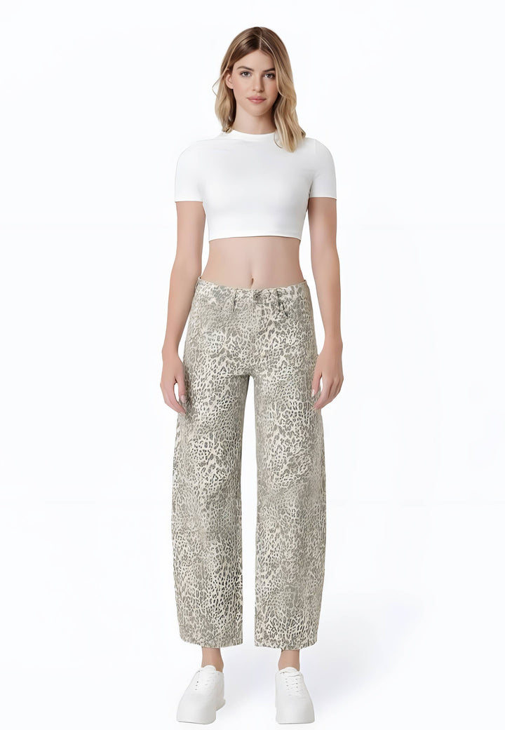 A model stands against a white studio background wearing a white short-sleeve crop top and beige-and-white animal-print wide-leg pants with white sneakers.