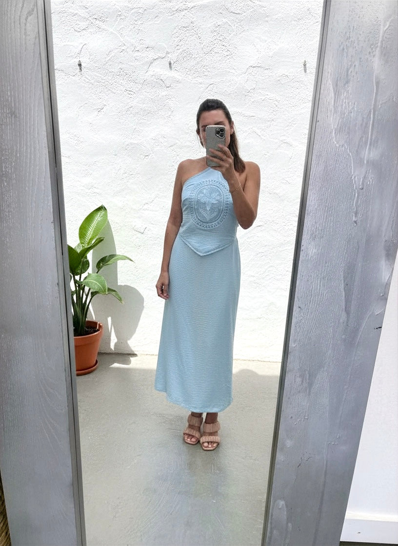 Woman wearing a light blue strapless dress taking a mirror selfie.