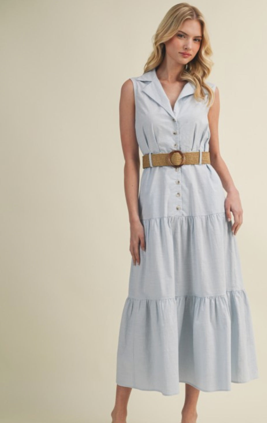 Woman wearing a light blue dress with a belt on a beige background