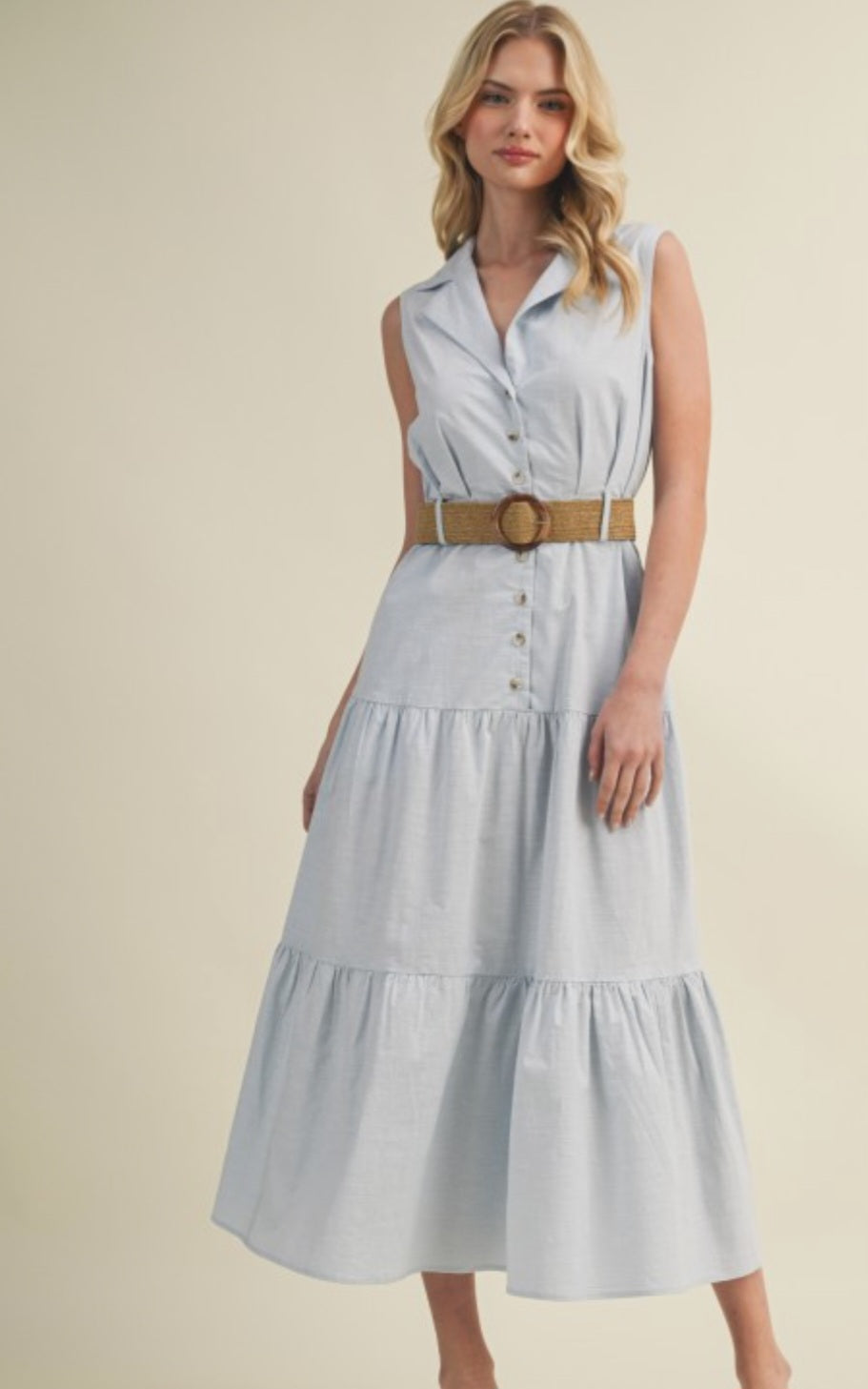 Woman wearing a light blue dress with a belt on a beige background