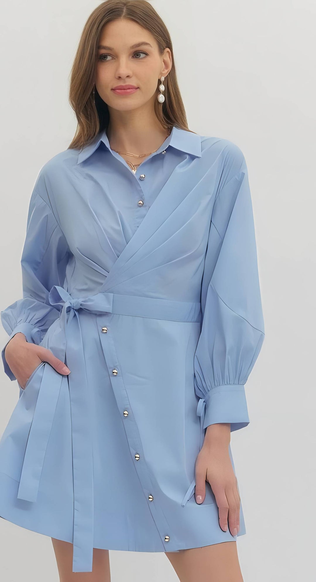 Woman wearing a light blue dress with a belt on a white background