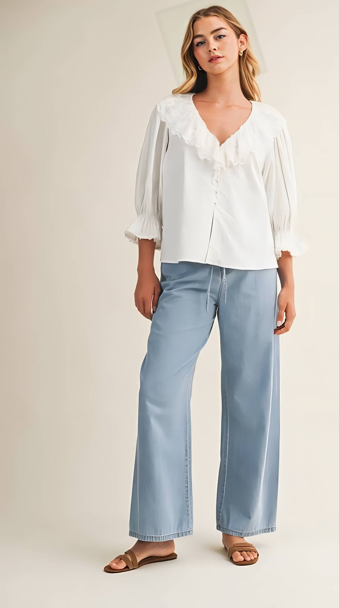 Woman wearing a white blouse and light blue jeans on a plain background