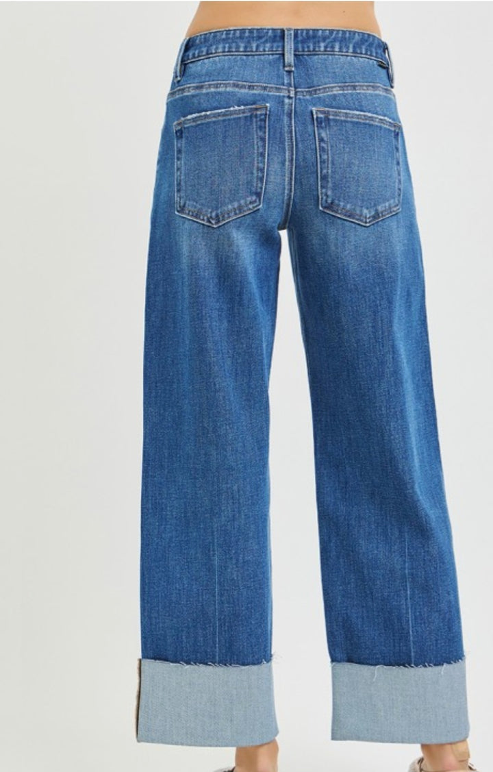 Blue jeans with rolled-up cuffs on a light gray background