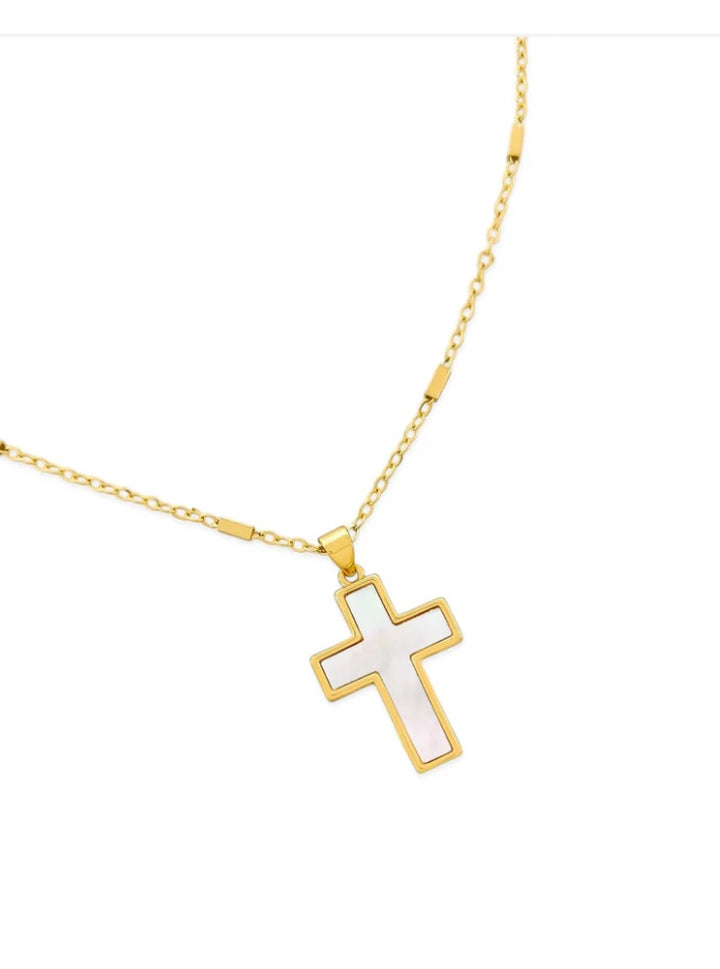 Gold necklace with a white cross pendant on a white background