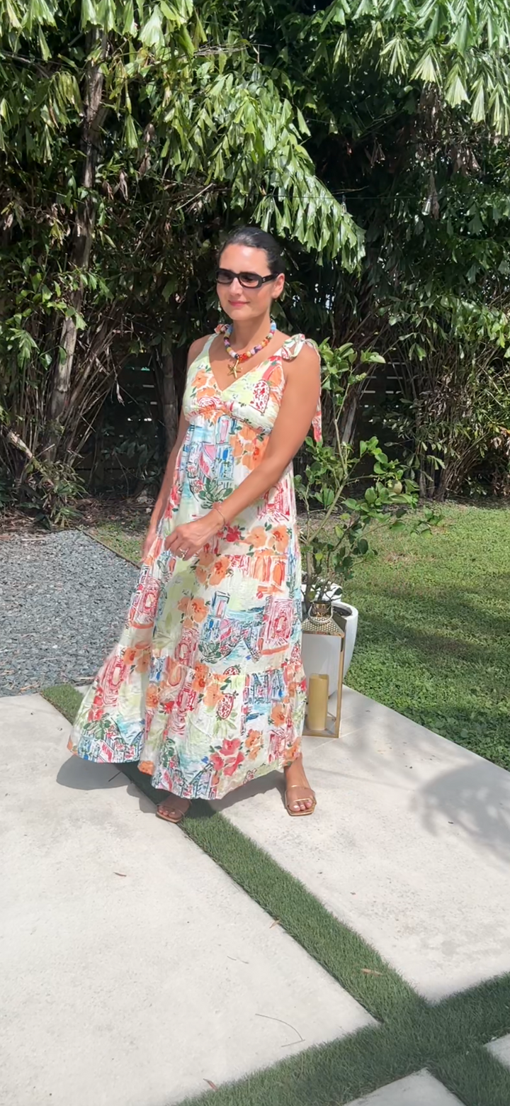 Woman in a floral dress standing outdoors with greenery in the background
