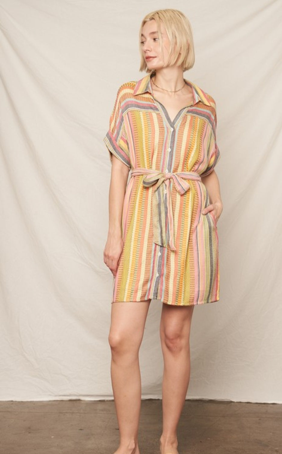Woman wearing a colorful striped dress against a plain background