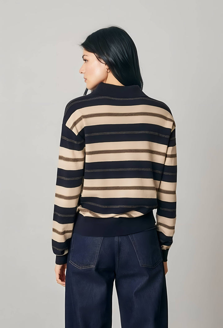 A woman shown from the back wearing a navy and beige horizontally striped knit sweater and dark navy wide-leg pants, photographed against a plain light gray studio background.