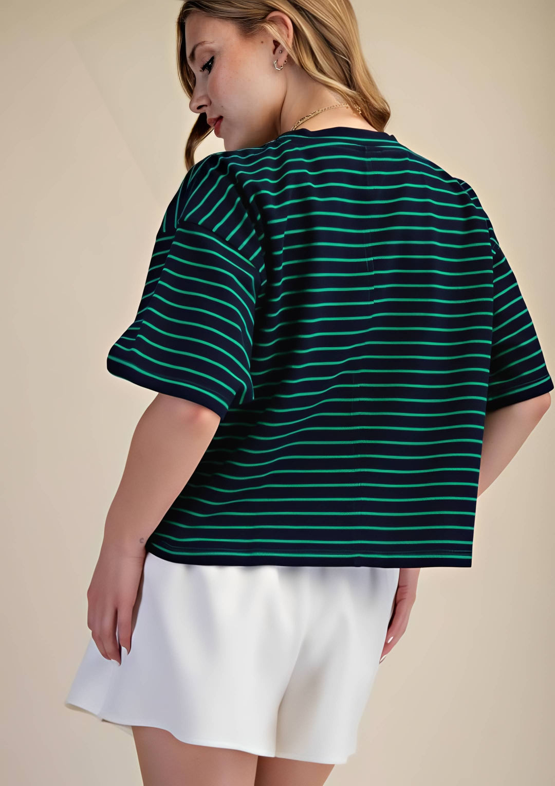 Woman wearing a green and navy striped shirt with a beige background