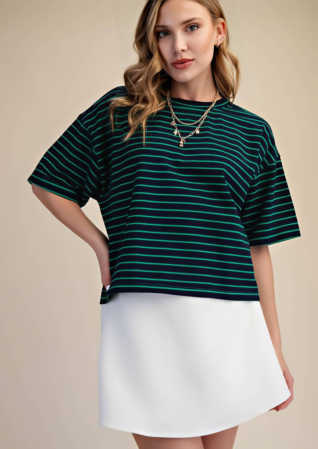 Woman wearing a green and navy striped top with a white skirt on a beige background