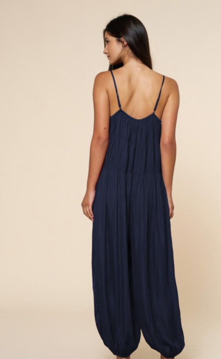 Woman wearing a navy blue jumpsuit on a beige background