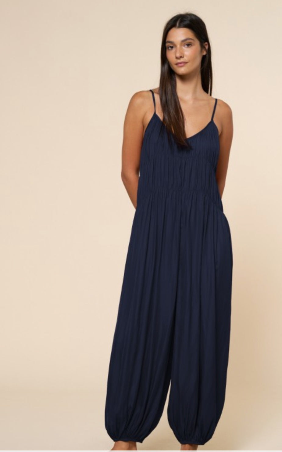 Woman wearing a navy blue jumpsuit on a beige background