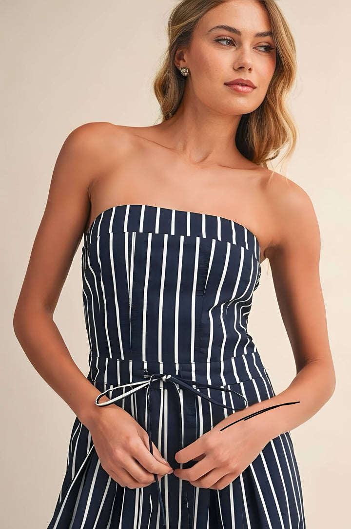 Woman wearing a strapless navy and white striped dress against a beige background