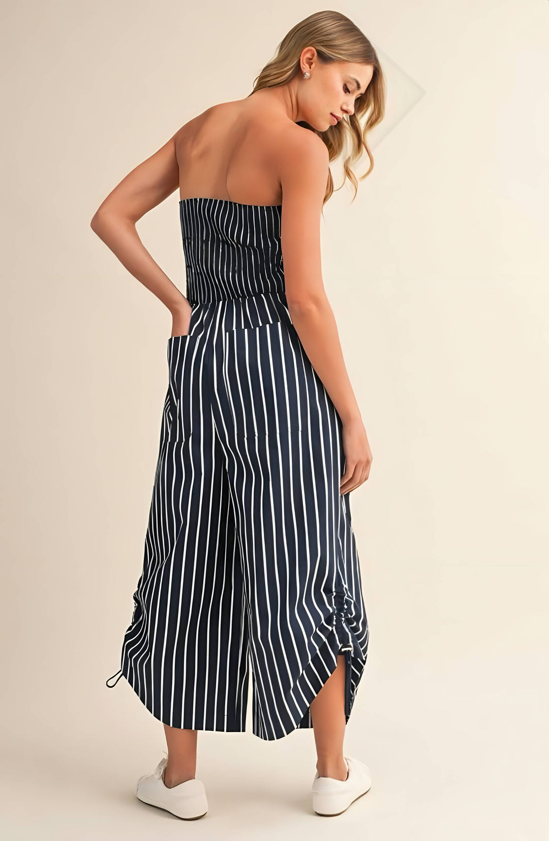 Woman wearing a strapless navy and white striped dress on a beige background