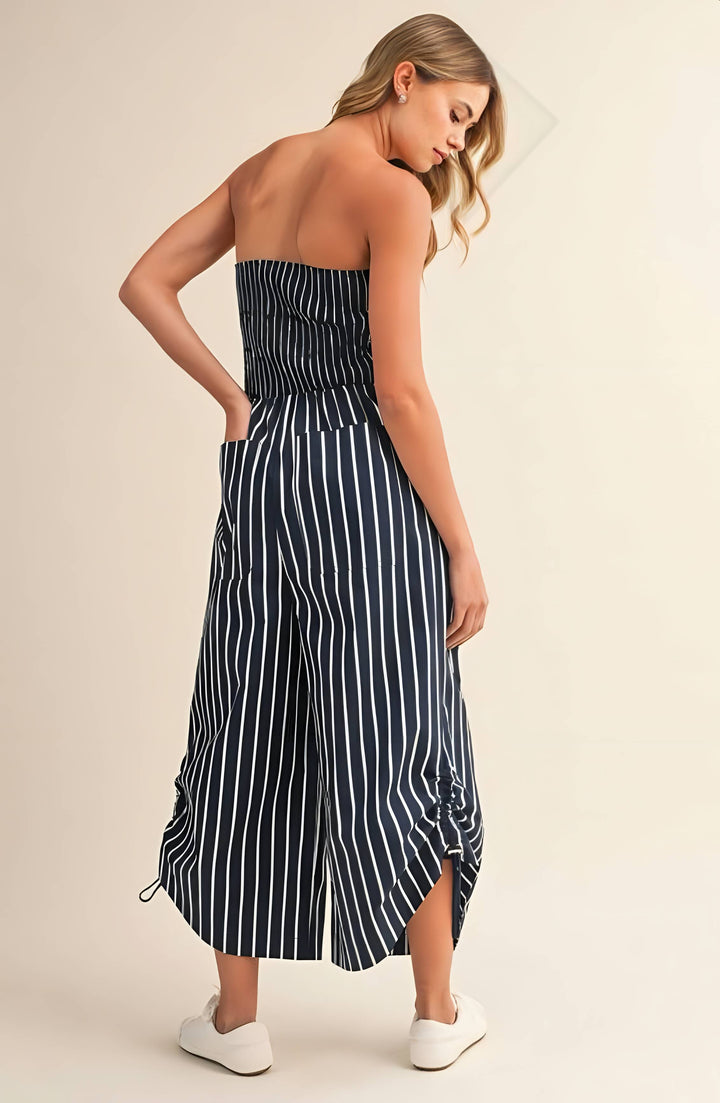 Woman wearing a strapless navy and white striped dress on a beige background