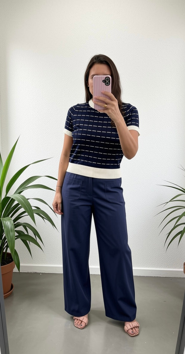 Woman wearing a navy stripe knit top with white hem sleeve and collar detail