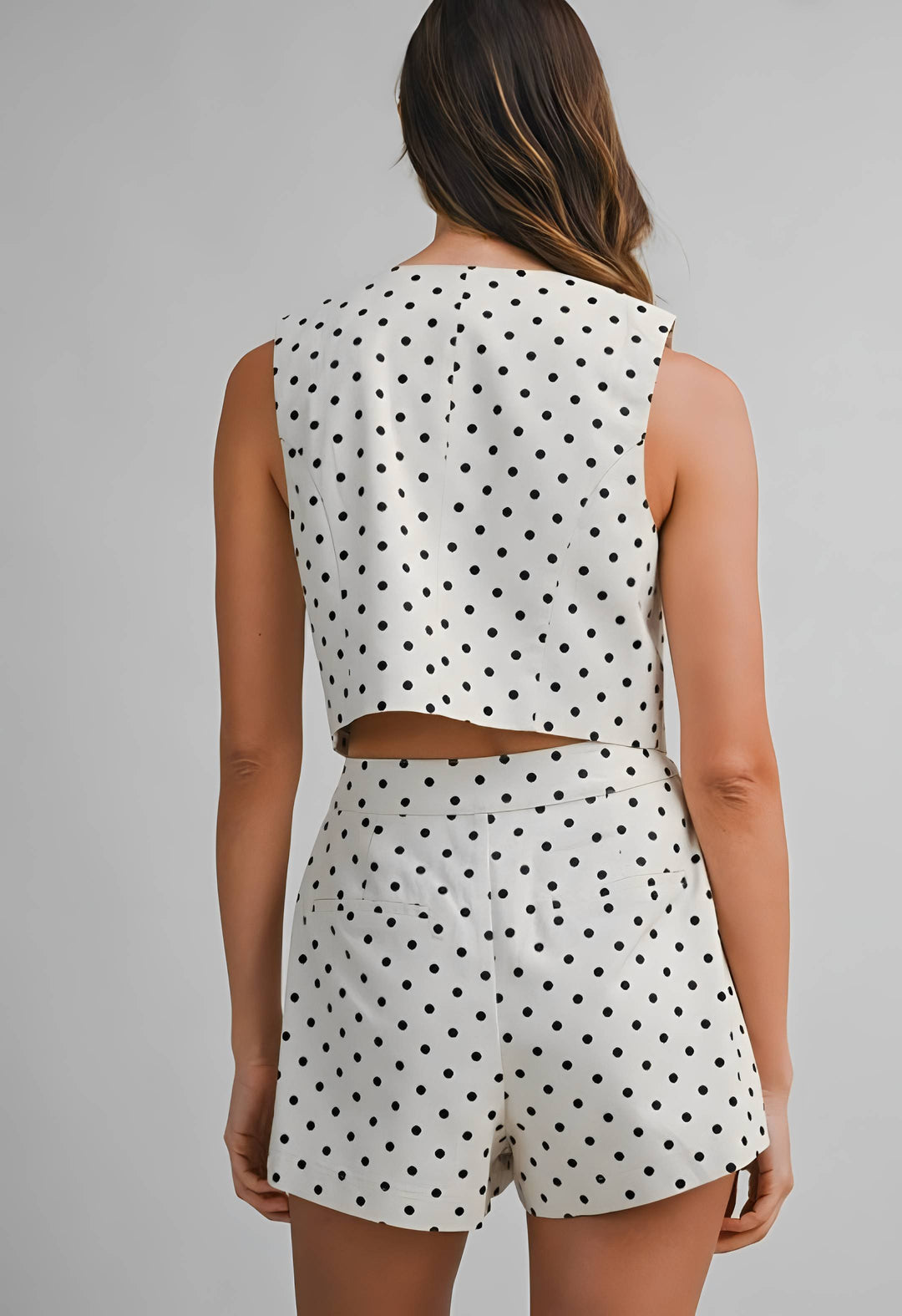 Woman wearing a polka dot romper on a gray background