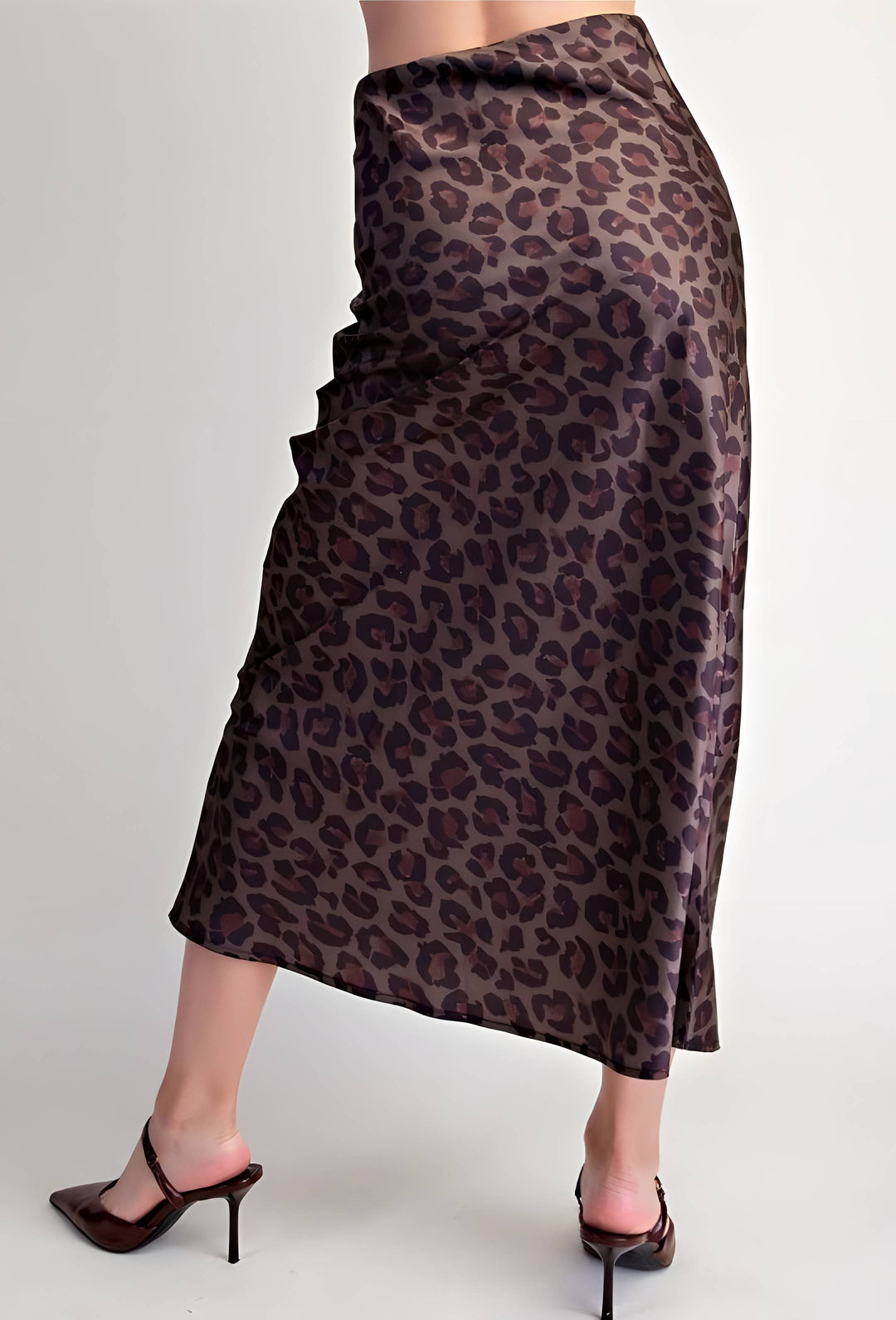 A leopard-print midi skirt in brown and black, shown on a model from the waist down wearing dark brown mule heels against a light gray background.