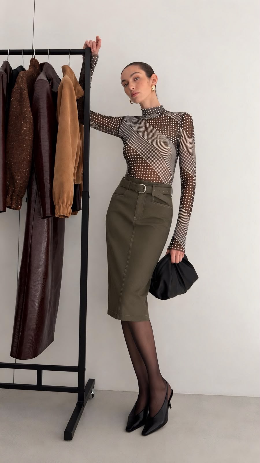 Woman wearing an olive mid lenght faux leather skirt with an abstract sheer top.