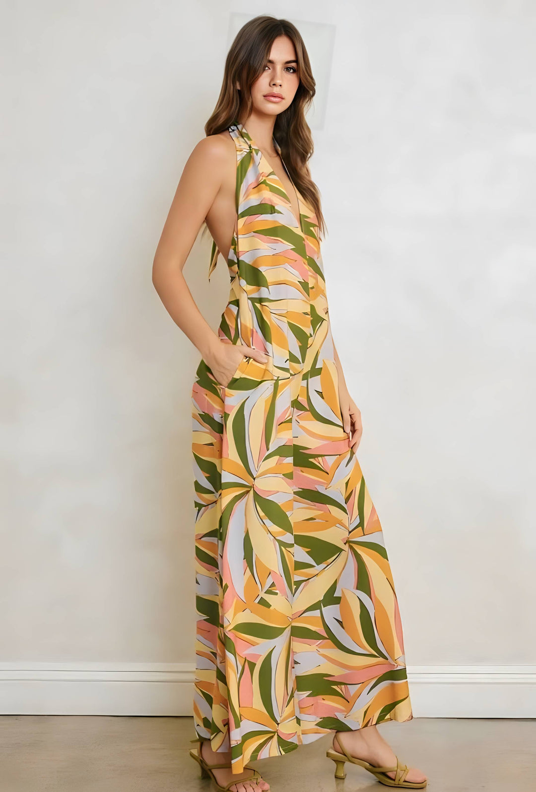 Woman wearing a colorful halter neck dress with leaf pattern against a plain background