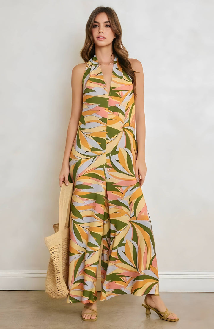 Woman wearing a colorful leaf-patterned jumpsuit against a plain background