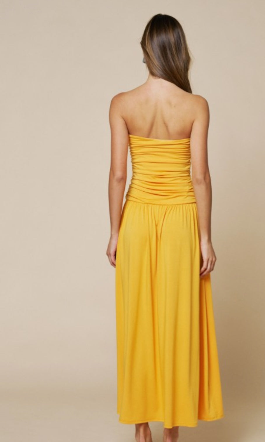 Woman wearing a yellow strapless dress on a beige background