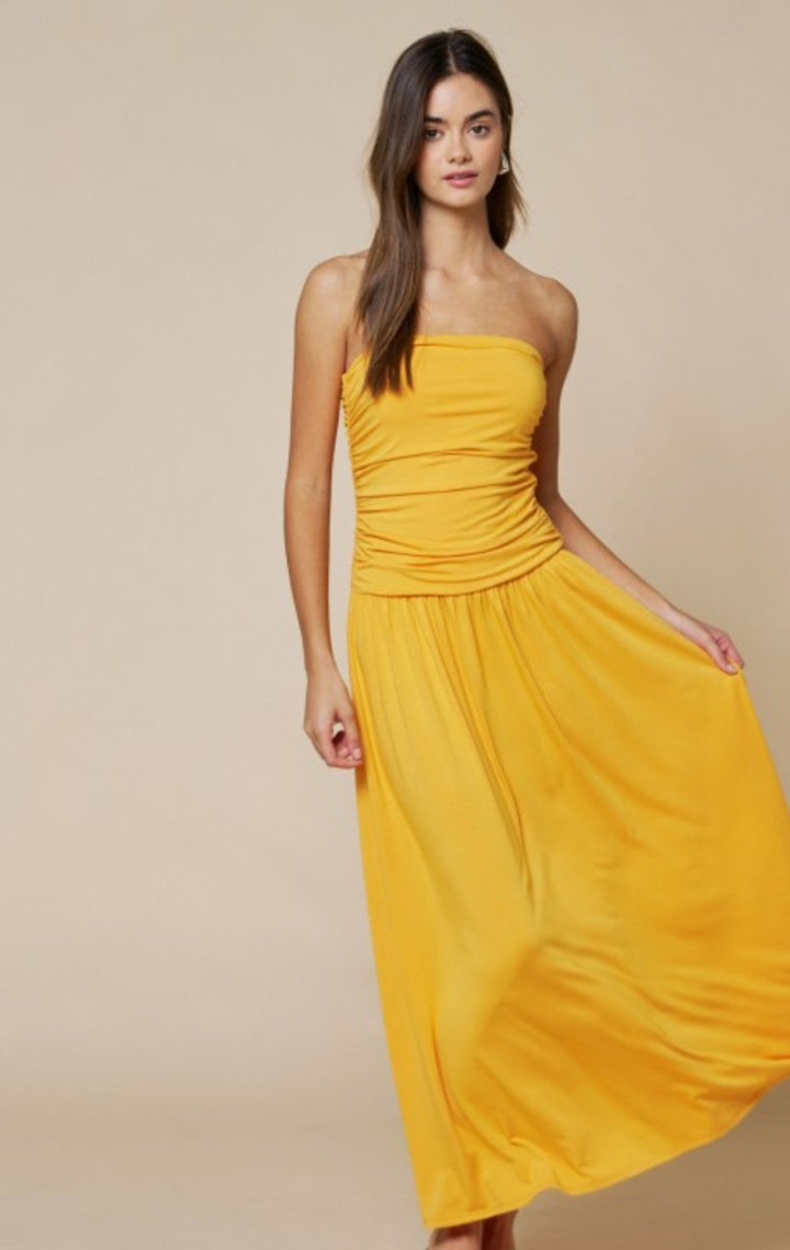 Woman wearing a yellow strapless dress against a beige background
