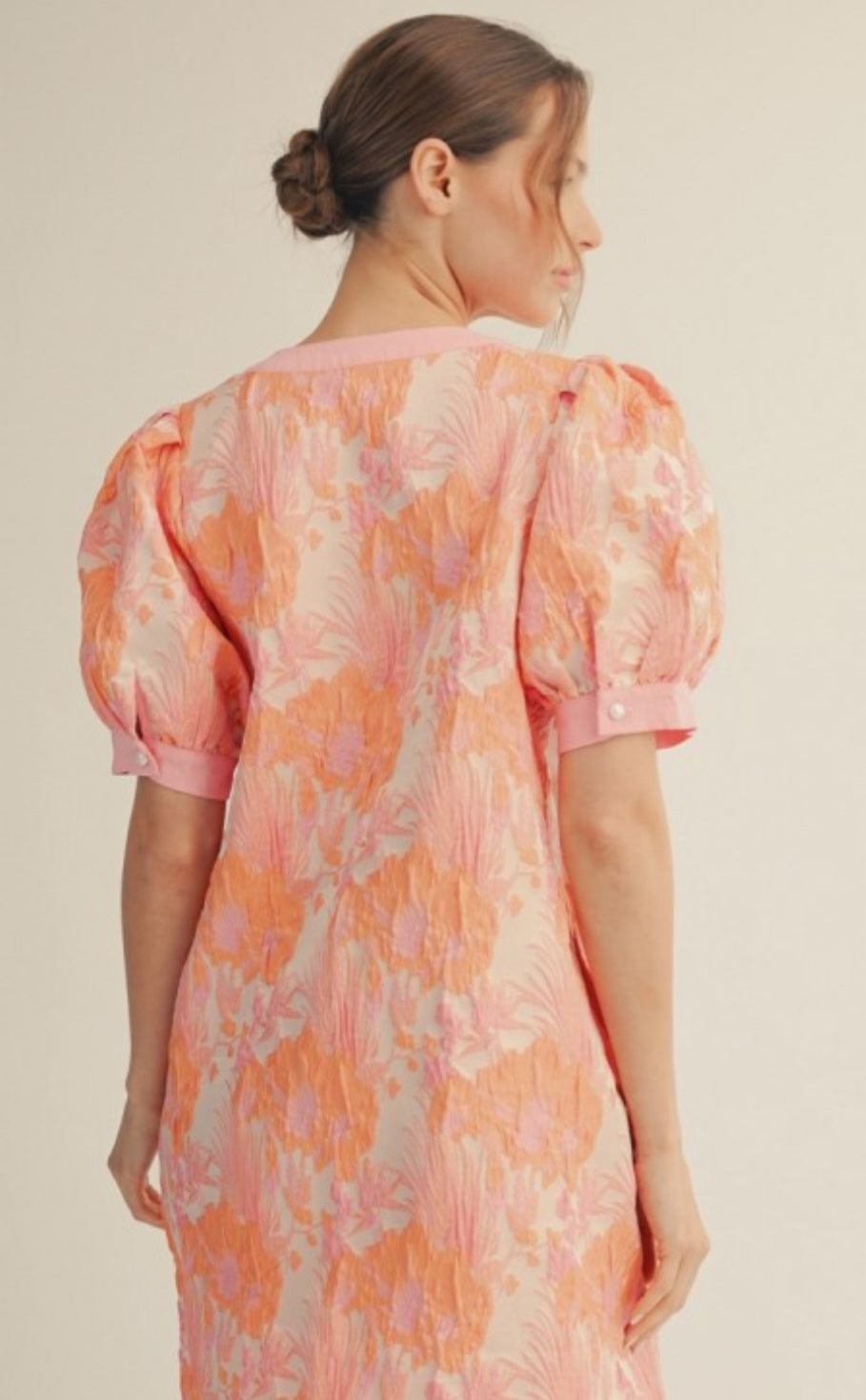 Woman wearing a floral dress with puff sleeves on a beige background