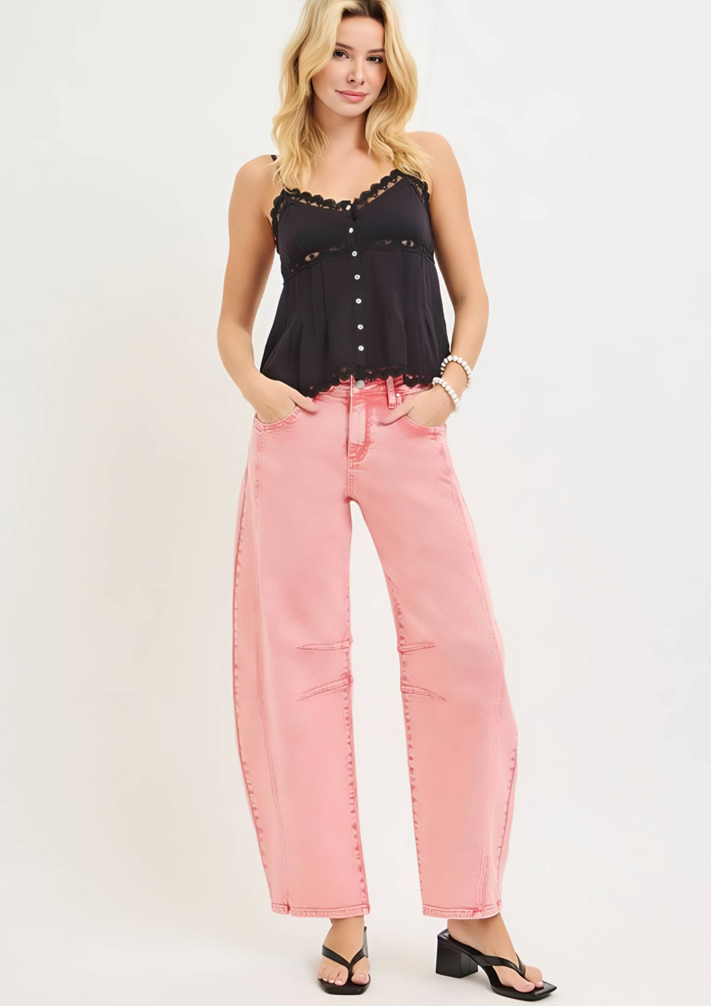 Woman wearing a black top and pink pants on a white background
