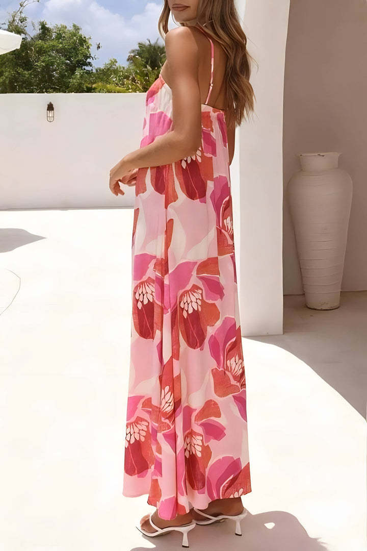 Woman wearing a floral dress in an outdoor setting with a white wall and greenery.