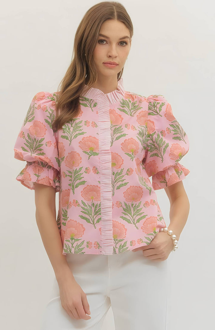 Woman wearing a pink floral blouse with ruffled sleeves on a white background