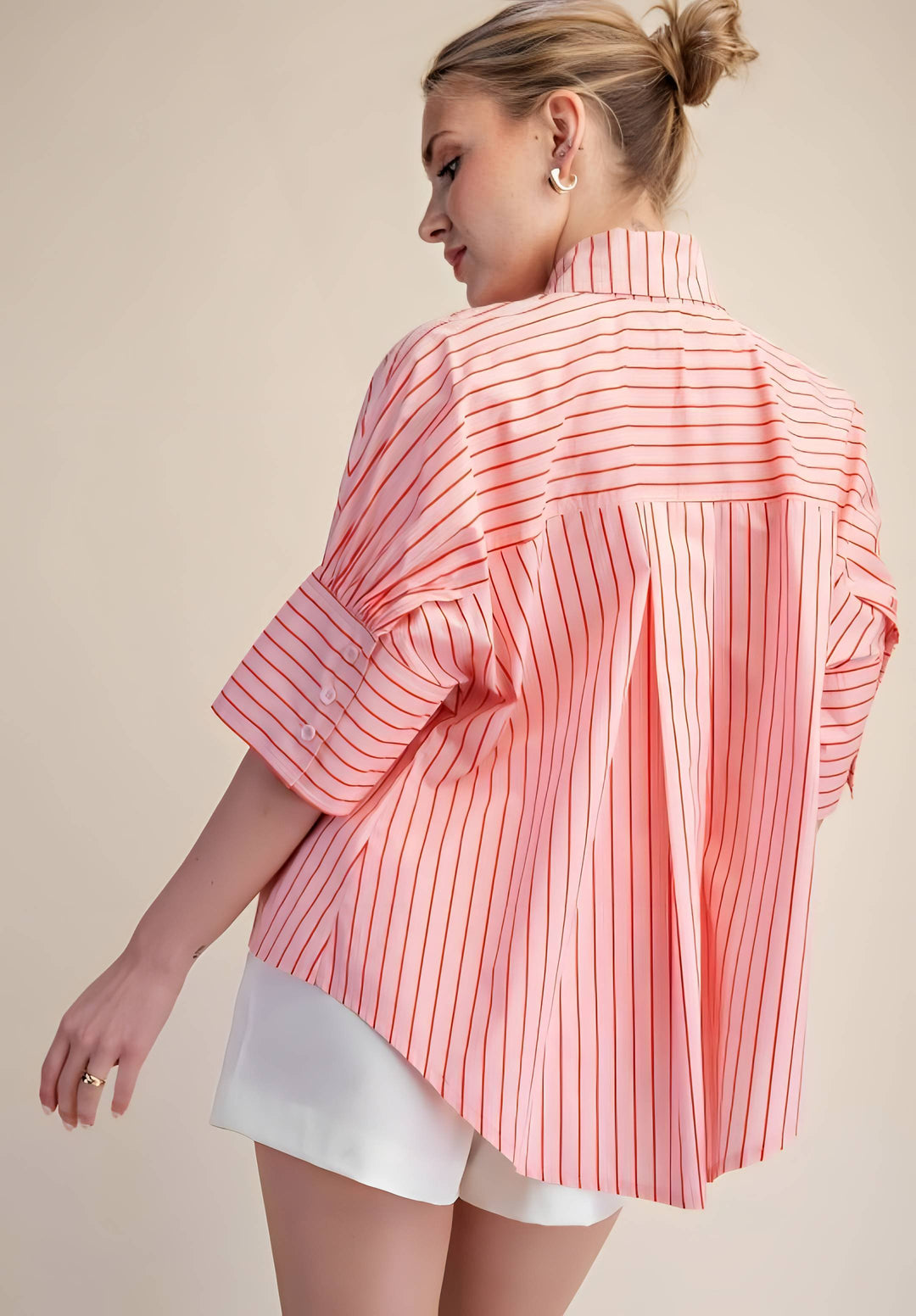 Woman wearing a pink and white striped shirt with a beige background