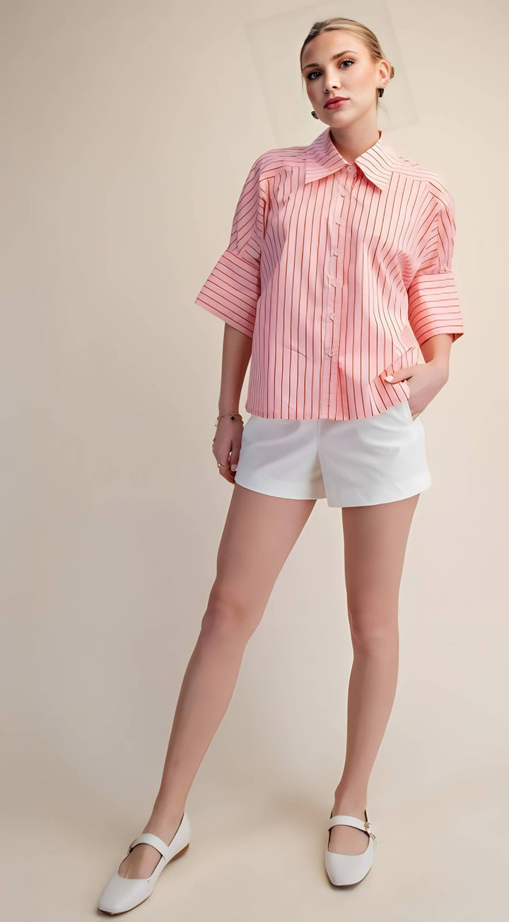 Woman wearing a pink striped shirt and white shorts on a beige background