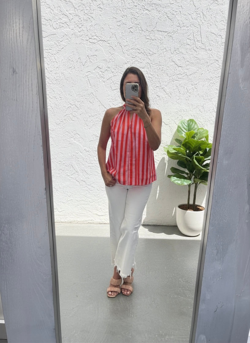 Person wearing a red and red striped top and white pants standing in front of a mirror.