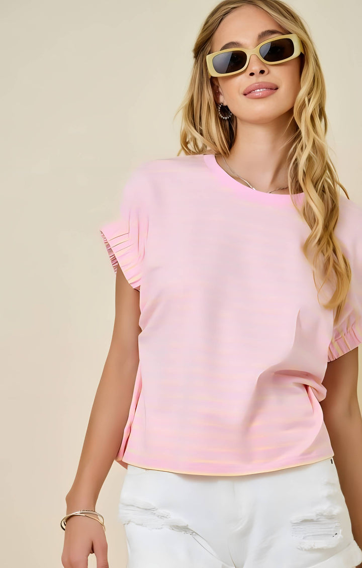 Woman wearing a pink top with ruffled sleeves and sunglasses on a beige background