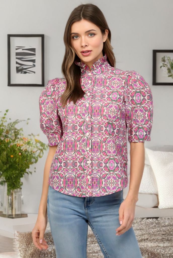 Woman wearing a patterned blouse and jeans in a room with decor elements.