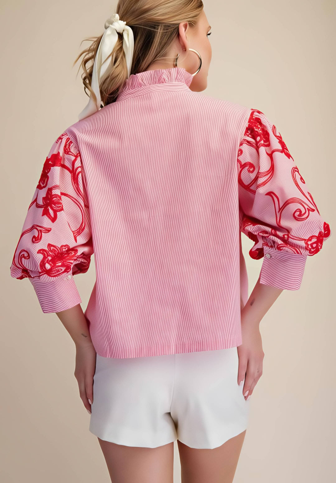 Woman wearing a pink blouse with red floral patterns on a beige background