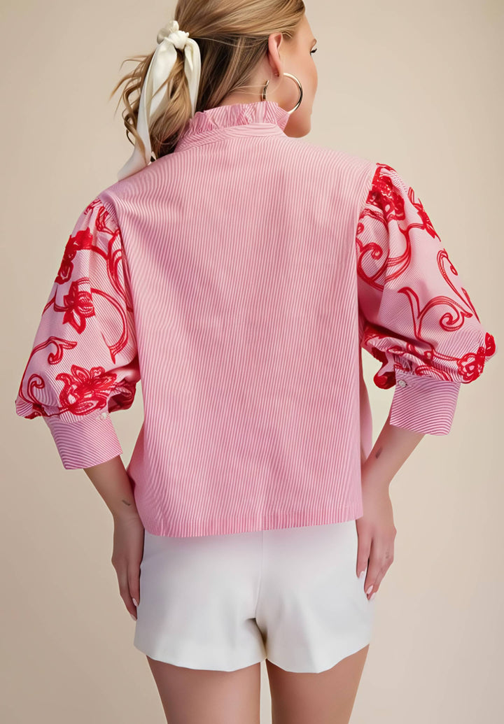 Woman wearing a pink blouse with red floral patterns on a beige background