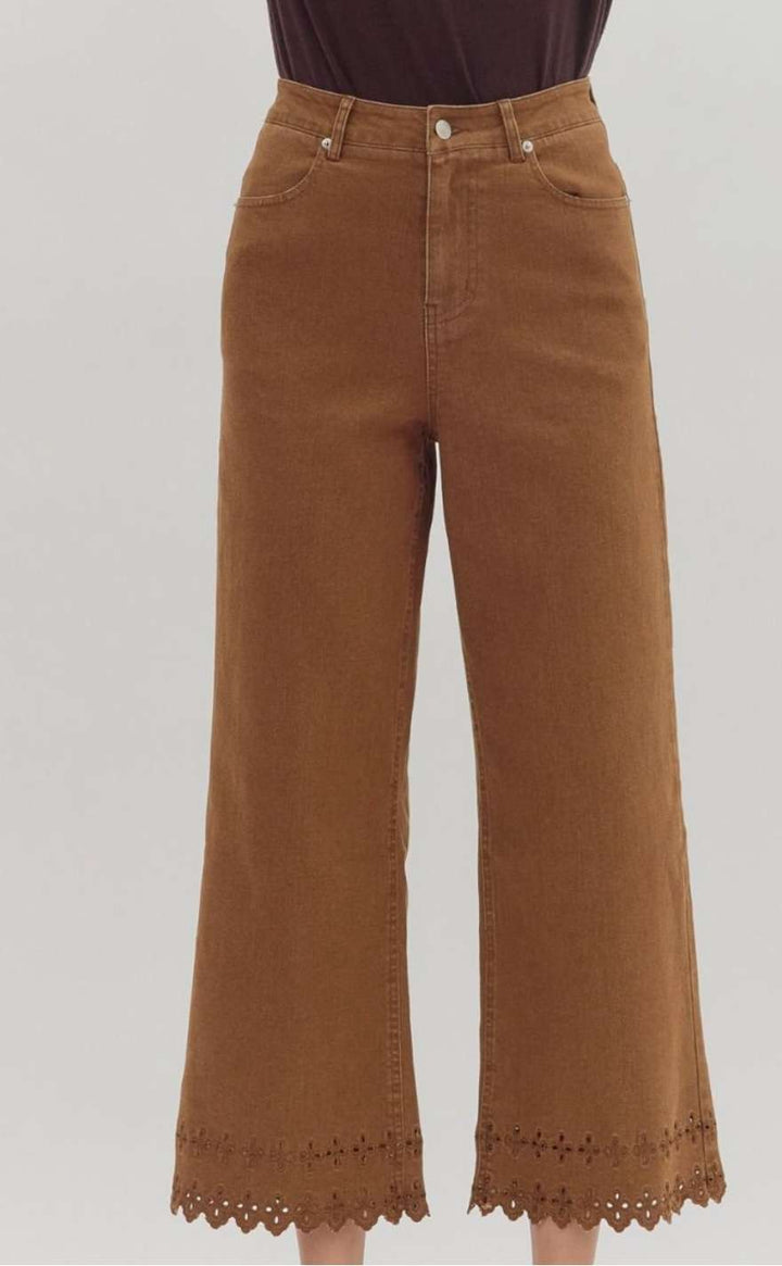 High-waisted brown denim pants featuring decorative eyelet hem